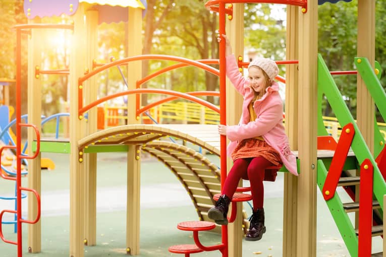 Une fille joue sur une aire de jeux dans un parc.