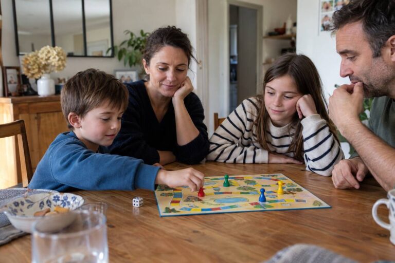 Quatre personnes sont assises autour d'une table en bois et jouent à un jeu de société coloré