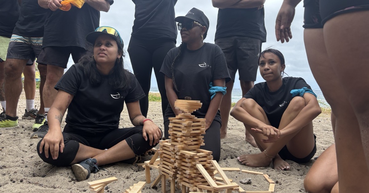 Équipe de collègues autour d'une tour de Kapla sur une plage de La Réunion lors d'un team building